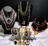 Wide view of multiple necklaces on busts, bracelets on display stand, rings and pendants on table