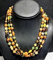 Full view of three-strand necklace on black mannequin showcasing multi-colored genuine stone and pearl beads in sterling silver setting.