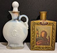 Front view of the two Jim Beam decanter bottles; milk glass bottle with stopper, and The Merry Lute Player bottle with gold textured finish and label