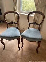 Front view of both walnut chairs with light blue upholstered seats and balloon back design