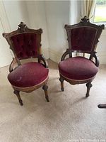 Front view of two matching walnut-framed chairs with red velvet upholstery