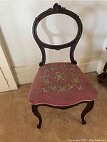Front angled view highlighting the carved walnut frame and needlepoint floral upholstery on the seat.