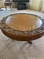 Top view showing round wooden tabletop with carved decorative border and water stains.