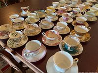 Overview of 35 assorted china cups and saucers on a dining table