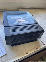 Top and side view of the black PhotoMaster Eliminator 3000W Digital Power Inverter showing logo and model information.