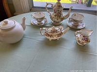 Full set displayed on tabletop: white coffee pot, Dresden porcelain tea pot, sugar bowl, creamer, two cups and saucers