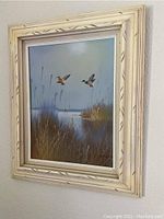 Frontal view of the framed duck painting showing two ducks flying over a marshland.
