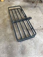 Full view of black steel cargo carrier laying flat on concrete floor