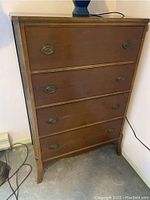 Front view of the carved mahogany 4-drawer high boy dresser with metal oval drawer pulls and curved legs.