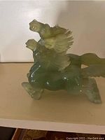 Side angle view of the translucent green onyx horses figurine with wings, showing detailed mane and muscular horse bodies.