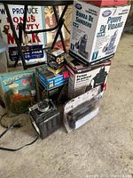 Photo showing three boxed submersible pumps, a golf clock sealed in plastic, a Yashica 35mm camera, a small box of pump washers, and an electric heater.