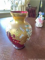 Front view showing ruby red interior and gold iridescent exterior with floral enamel decoration