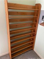 Front view of solid pine shoe rack with 9 slatted shelves, natural wood color, set against a wall.