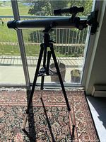 Side view of the full telescope setup on tripod near a window.