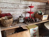 Shelf with various antique items including bread bin, tiered candy stand, box of old door knobs, glass oiler, burl pieces