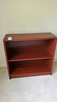 Front view of a reddish-brown wooden bookshelf with one adjustable shelf.