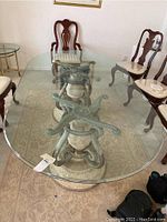 Top view of the oval beveled glass dining table showing the full glass surface with minor scratches and clear visibility of the ceramic/stone base underneath.