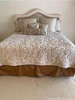 Front view of king size bed with upholstered headboard, bedding set, pillows, and bed skirt.