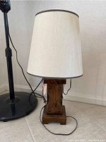 Full view of the wooden table lamp with cream fabric shade and dark brown trim