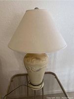 Full view of beige ceramic lamp with fabric shade, showing size and shape.