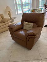 Front view of the brown leather La-Z-Boy rocker recliner showing the cushion, armrests, and pillow
