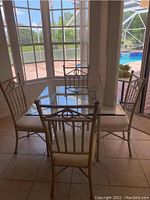 Full view of the metal painted dining table with beveled glass top and four chairs arranged around it, showing overall condition and style.