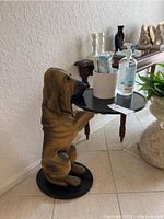 Front angle view of resin dog side table holding round tray and items