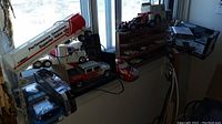 Overall display of model cars and trucks on window ledge and shelves including a large white gas tanker trailer, various trucks and cars