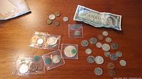 Overview of assortment including coins in plastic holders, loose coins, and the Centennial dollar bill on a wooden surface.