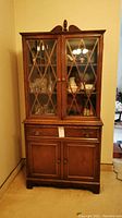 Full view of wooden china cabinet buffet with glass doors, lattice design, drawer, and lower cabinet. Shows overall condition including scratches.