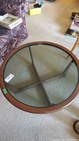 Top view of the round coffee table showing the smoked glass surface and wooden rim.