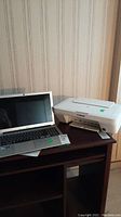 Acer laptop and Canon printer on wooden desk against wallpaper background.