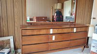 Front view of wooden dresser with mirror showing nine drawers and tapered legs