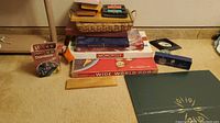 Photo showing the stacked games including Monopoly, Wide World, Scrabble, Dominoes, Cribbage, cards in basket, and Tumbling wooden blocks set