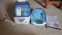 Vicks Cool Mist Humidifier with detachable water tank and instruction manual laid out on carpeted floor.