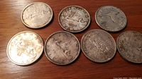 Group of seven silver dollars arranged on wooden surface