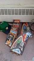 Overview of the lot showing multiple Star Trek paperback books, two action figures in packaging, and a green Spock hat.