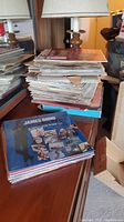 Large stack of vinyl records piled on a table, shows general quantity and condition.