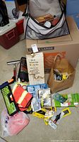 Overview photo showing assorted items including a cardboard box, a safety vest, assorted hardware items, and a paper bag filled with smaller items.