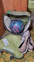Sears bowling ball inside open carrying case with metal holder. Pair of worn Brunswick bowling shoes beside the case.