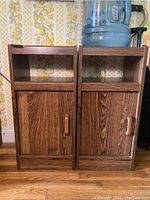 Pair of woodgrain composite laminate cabinets placed side by side, showing front view with closed doors and open shelves on top.
