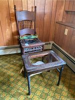 Photo showing the wooden chair and footstool with woven seats, both damaged and worn.