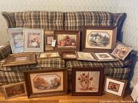 Wide shot of all 15 framed prints arranged on a sofa and floor showing various sizes and subjects