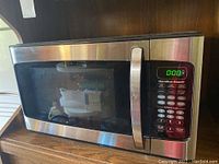 Front view of the Hamilton Beach microwave showing the door, handle, and control panel with digital display.
