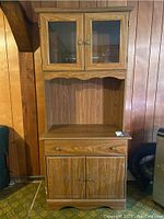 Front view of wooden hutch showing glass upper cabinet doors, drawer, and lower cabinet doors