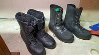 Two pairs of men's rubber boots: one insulated and lined for cold weather, the other plain black rubber lace-up boot.