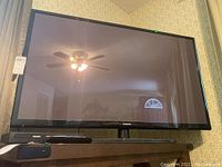 Frontal photo of Samsung 51 inch plasma TV showing screen and TV stand base on wooden table.