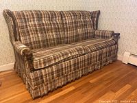 Front view of the weathered plaid fabric sleeper sofa with rolled arms and tufted backrest.