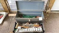 Opened metal toolbox showing interior with assorted hand tools and socket set