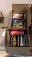 Top-down photo showing the two boxes filled with assorted books, diverse genres visible.